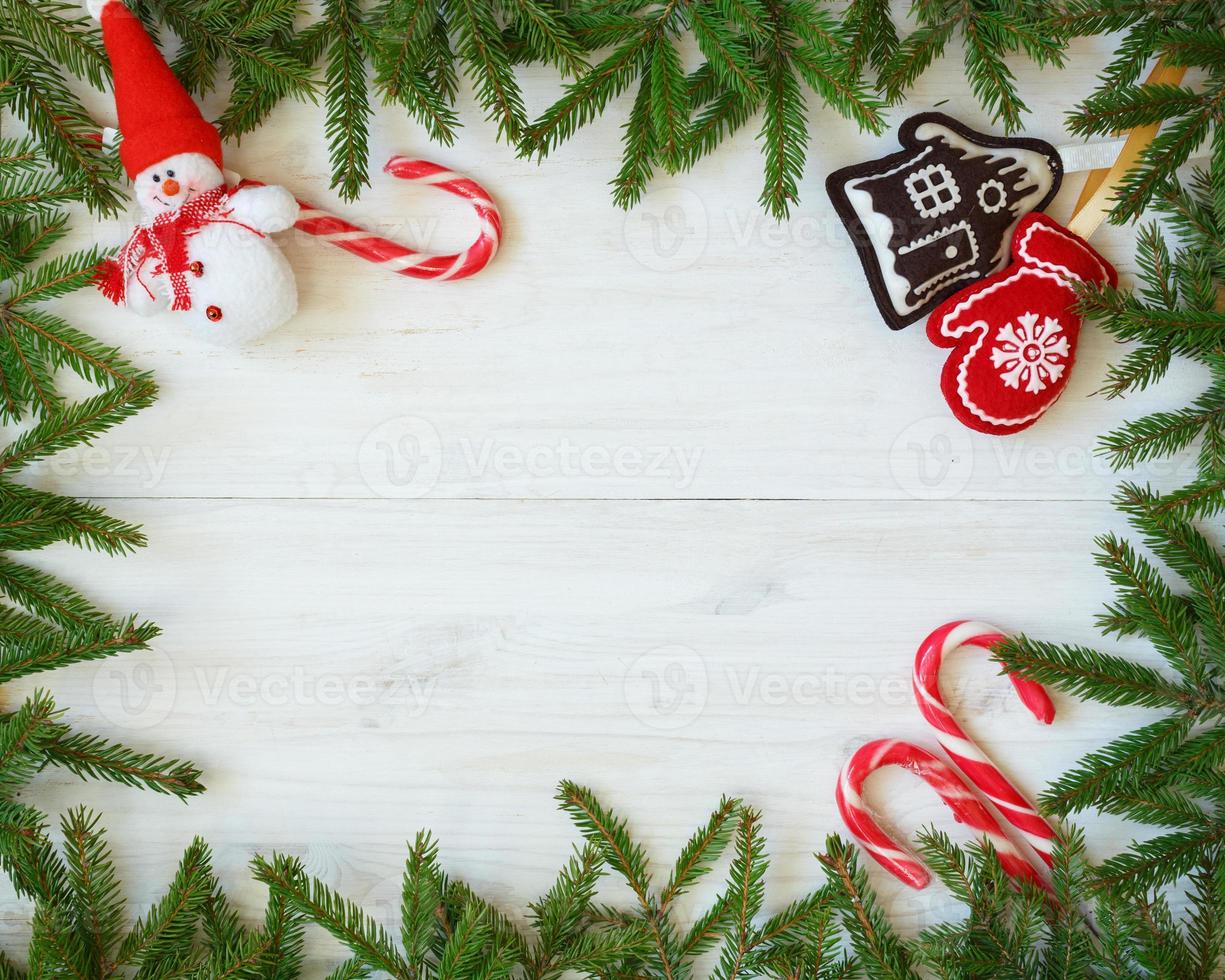 Christmas border with fir tree branches, christmas decorations and candy cane on white wooden boards photo