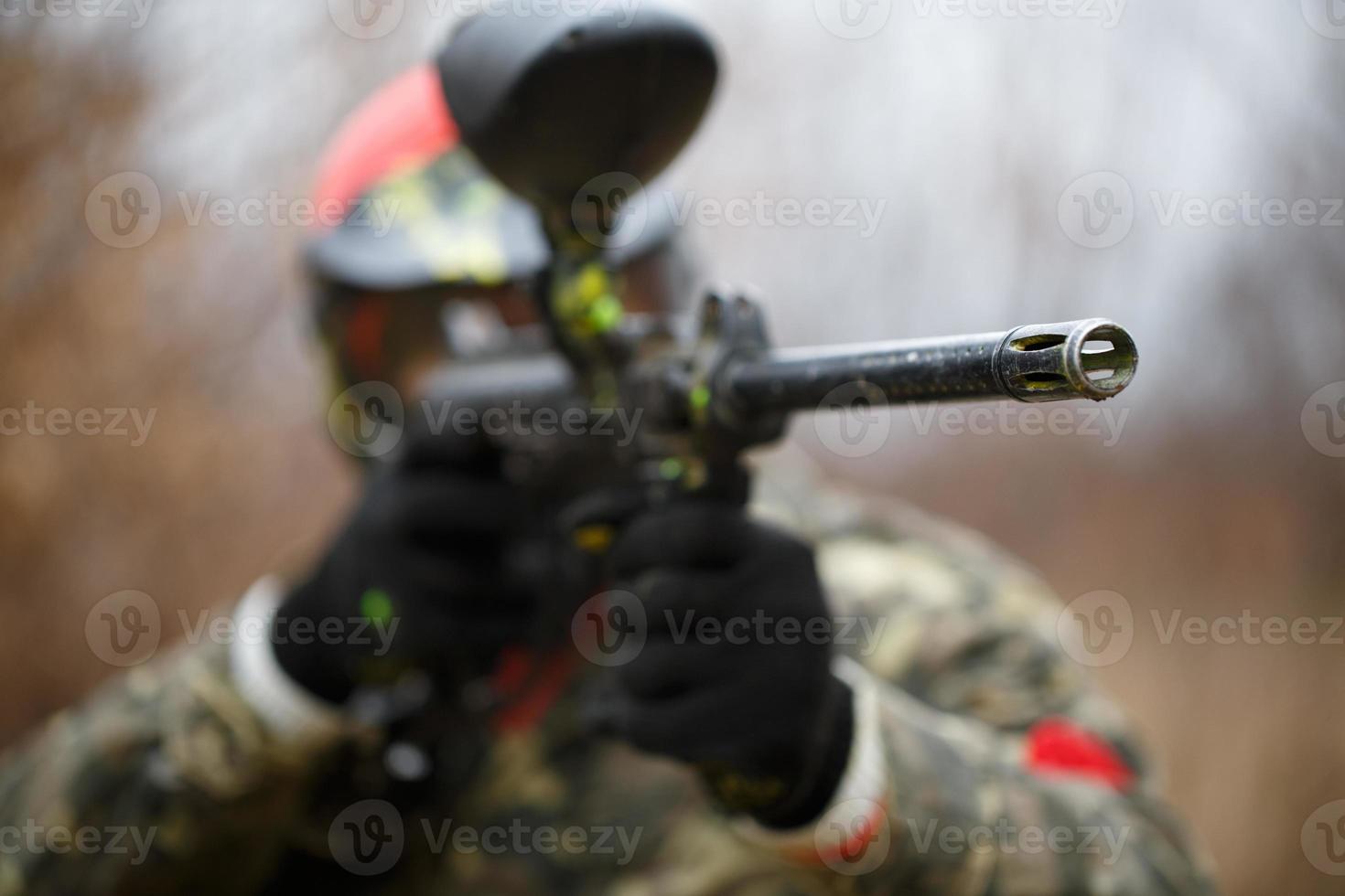 Paintball sport player wearing protective mask and aiming gun photo