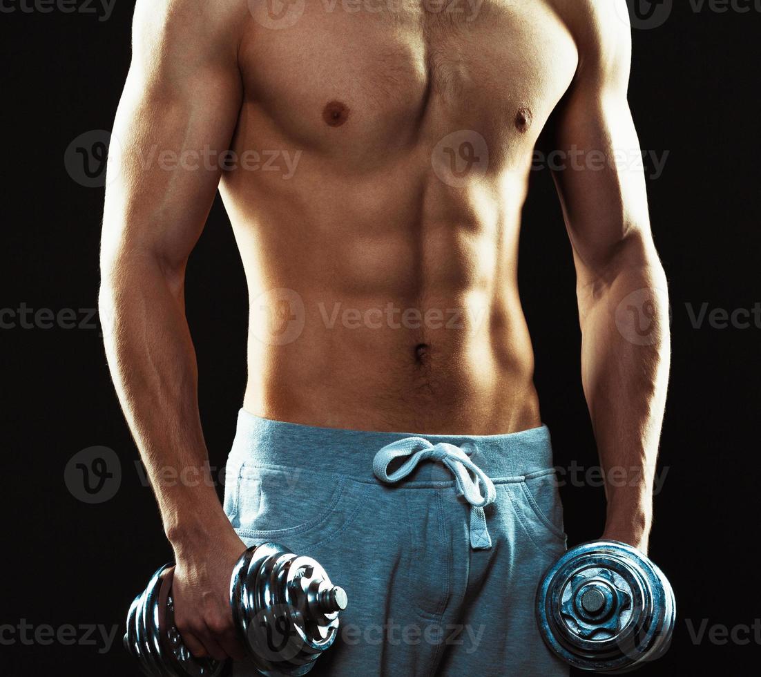 atlético hombre con pesas en el negro foto