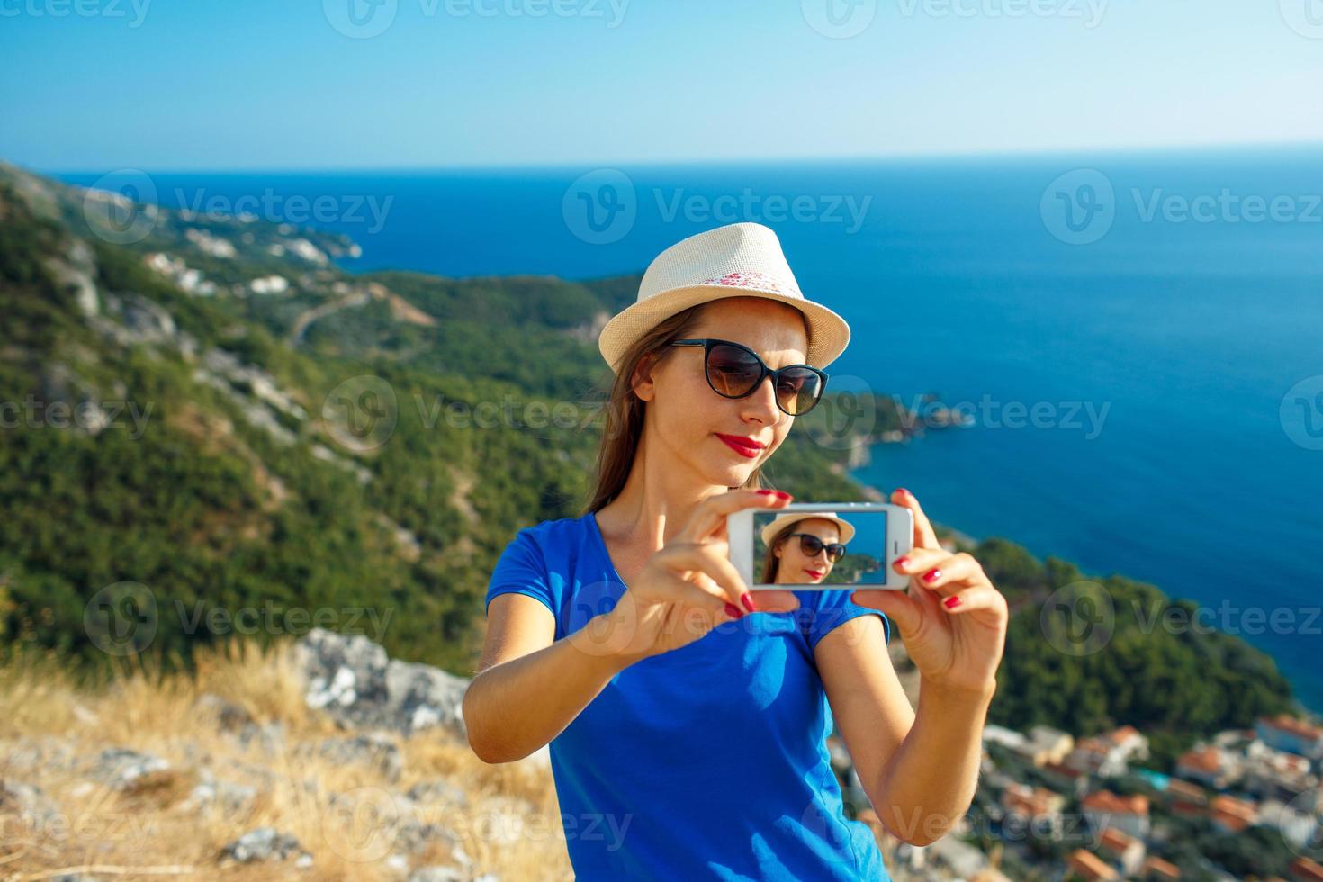 Girl in the hat making selfie by the smartphone on the background of sea coast, Adriatic sea photo