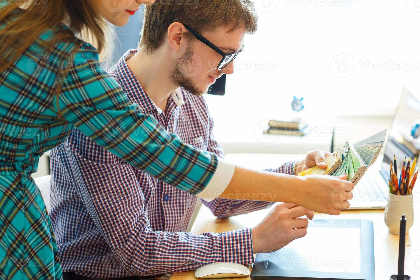 Young colleague looking to a color paint palette at home office photo