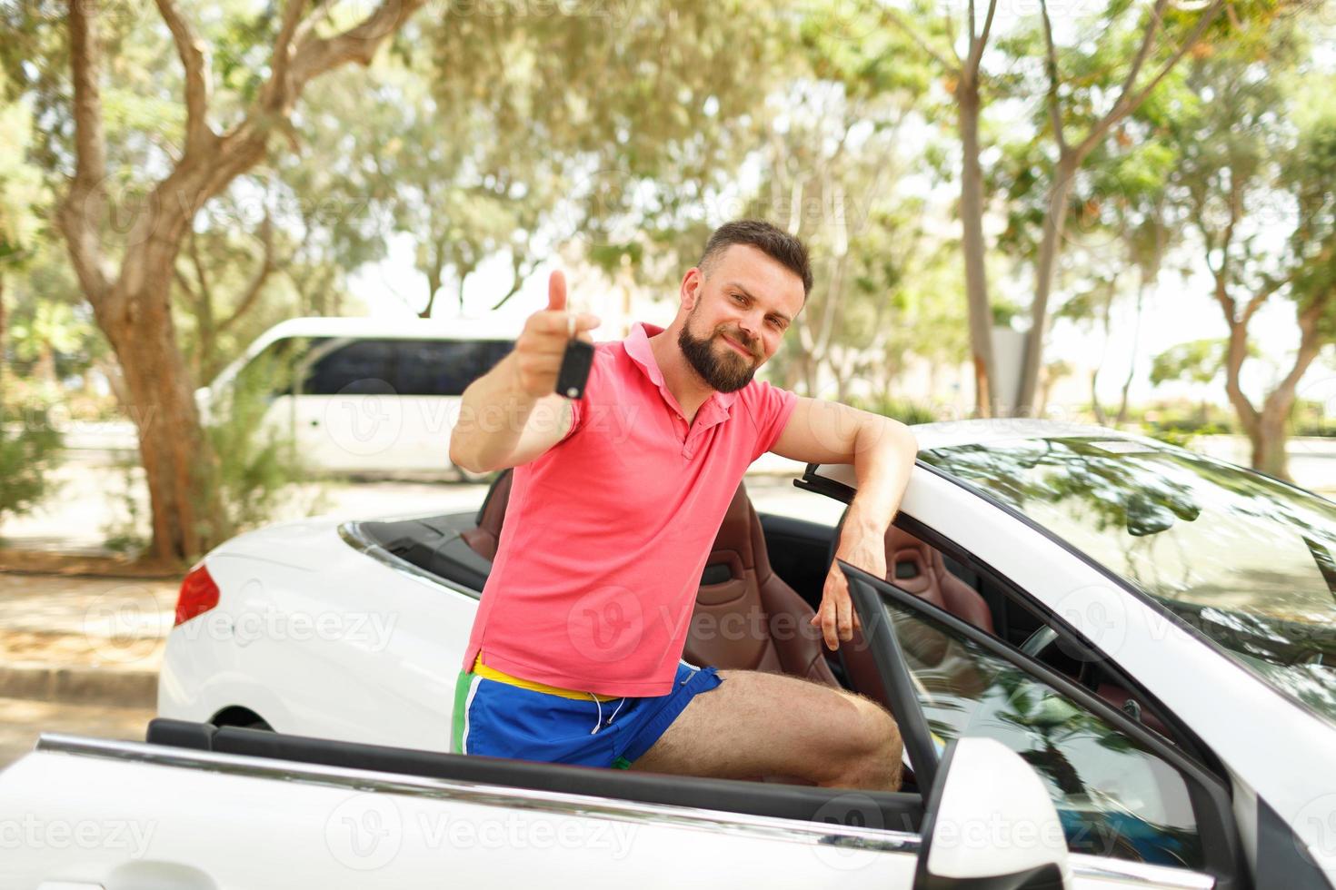 Bearded man standing near convertible with keys in hand photo