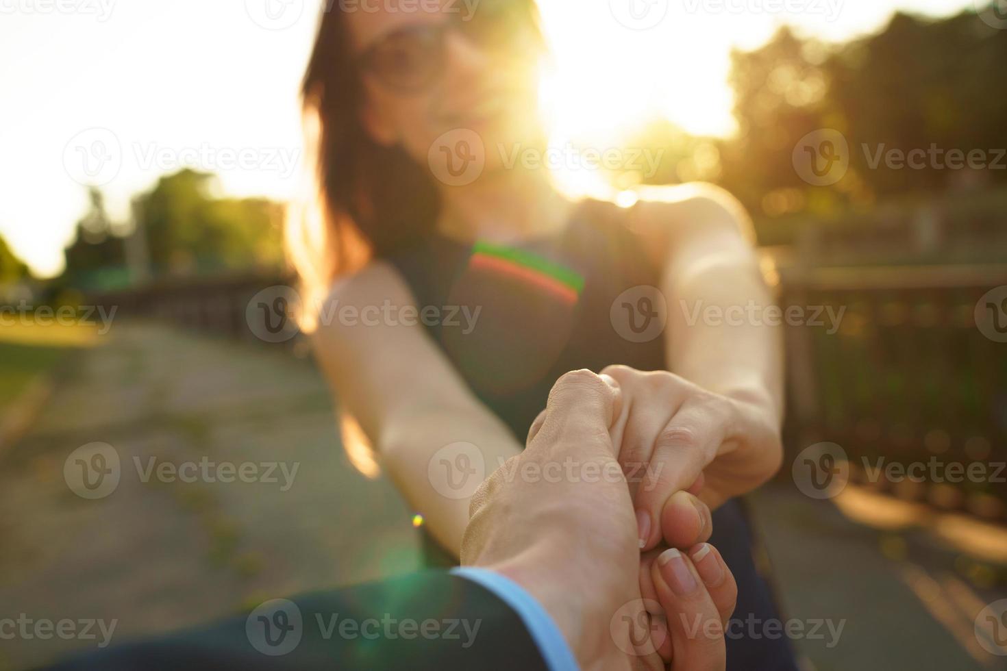 Follow me - happy young woman pulling guy's hand - hand in hand walking on a bright sunny day photo