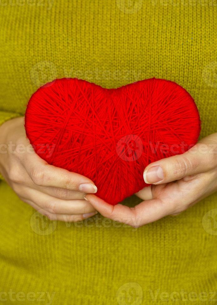 Closeup on red heart made from wool in hand of woman photo