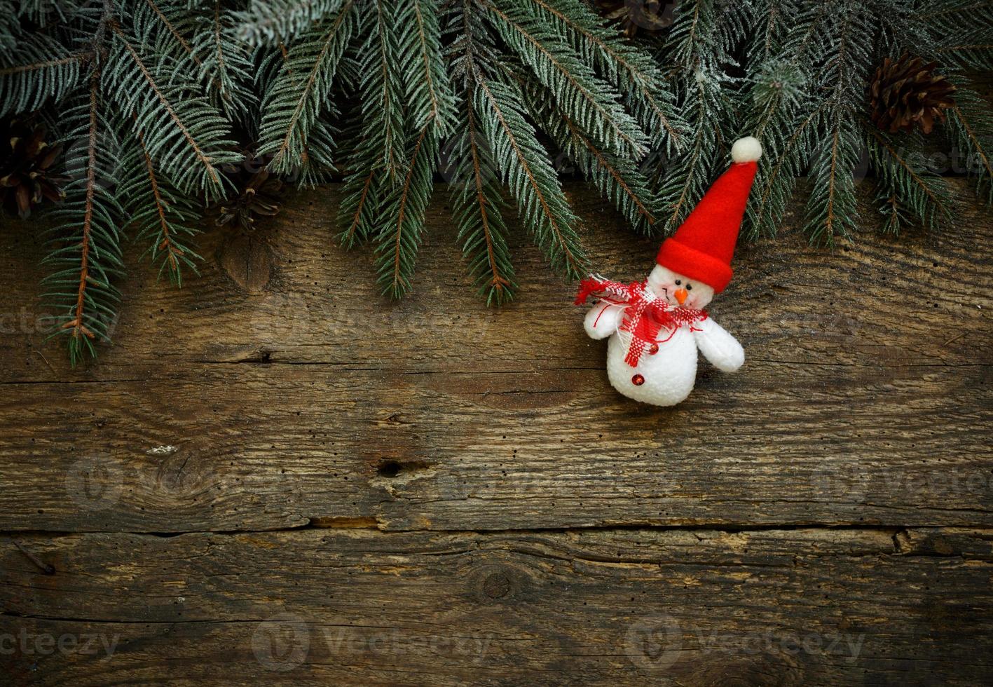 Christmas tree branches with snowman on wooden texture photo