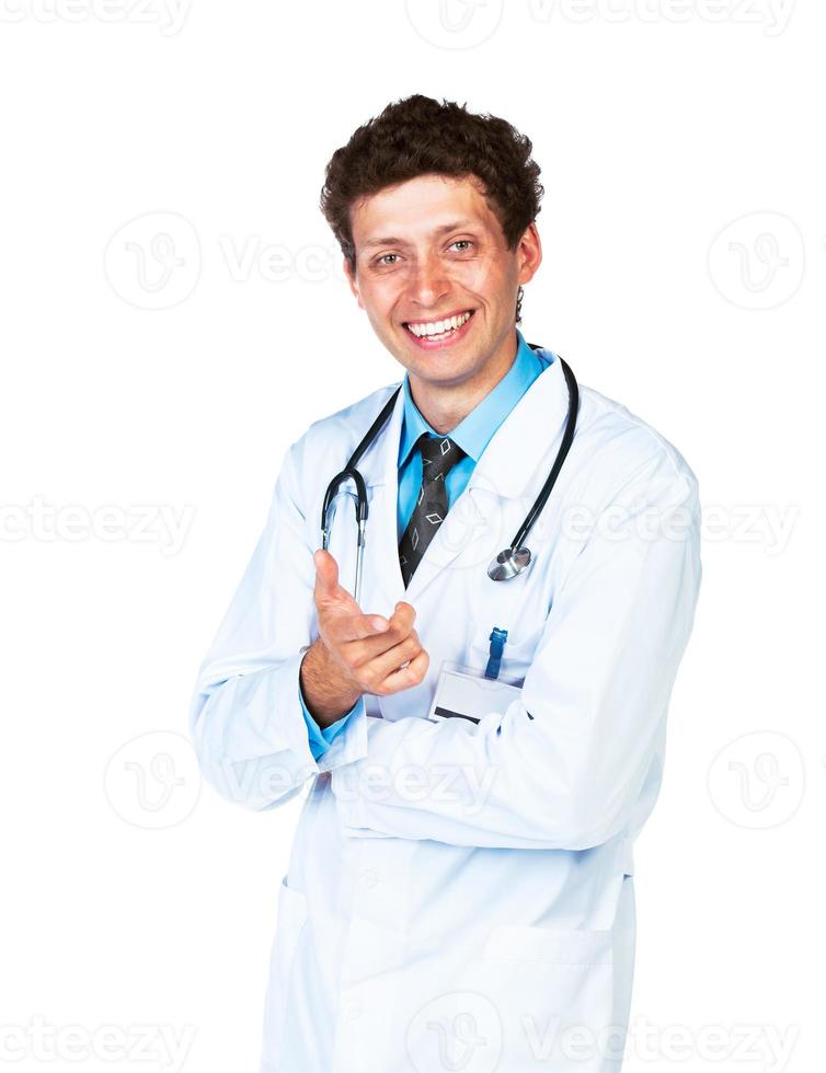 Portrait of a smiling male doctor showing finger at you on white photo