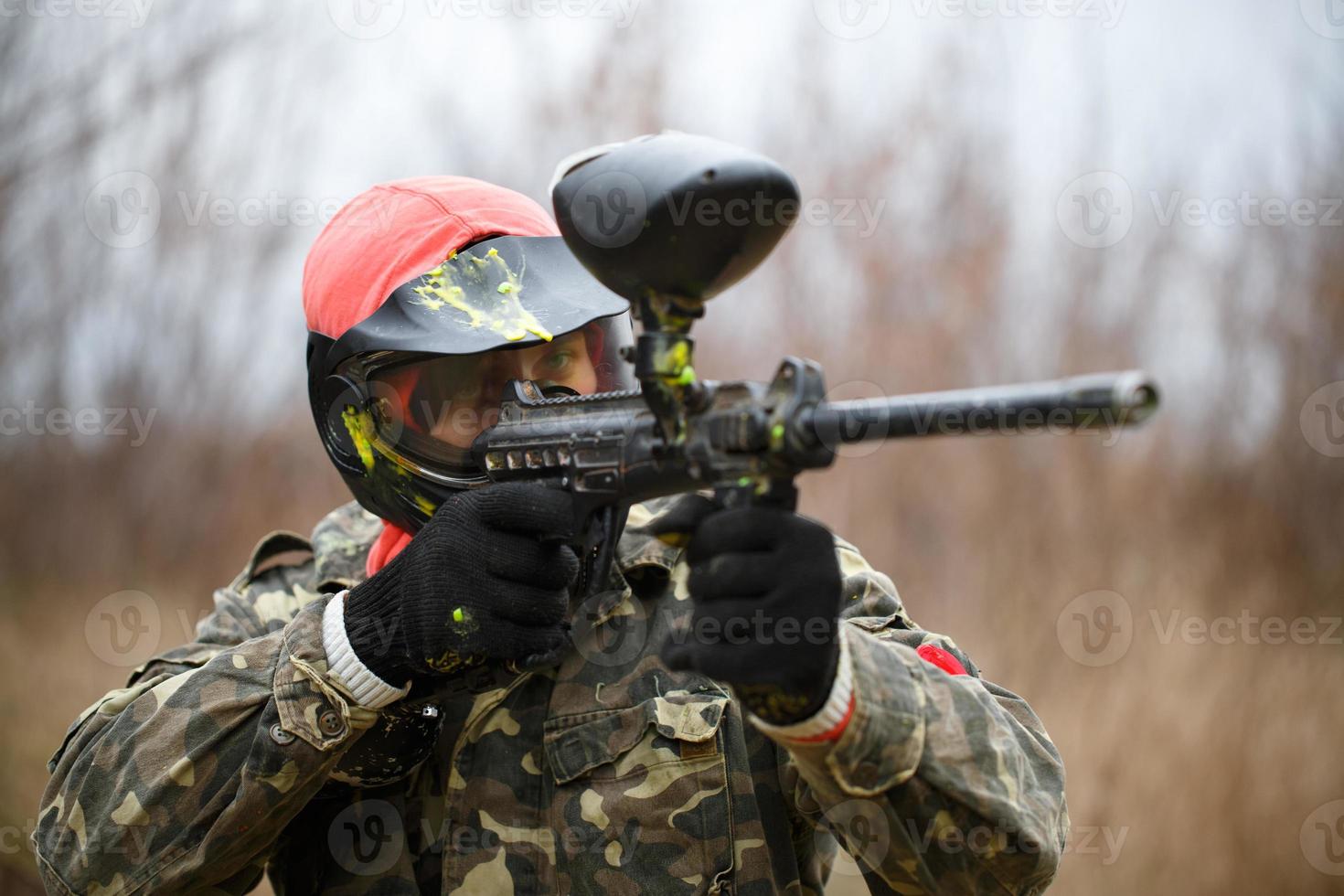 Paintball sport player wearing protective mask and aiming gun photo