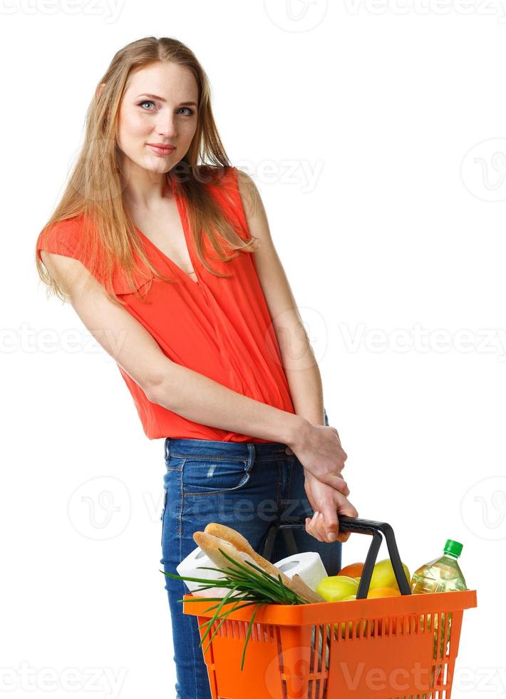 Happy young woman holding a basket full of healthy food on white. Shopping photo