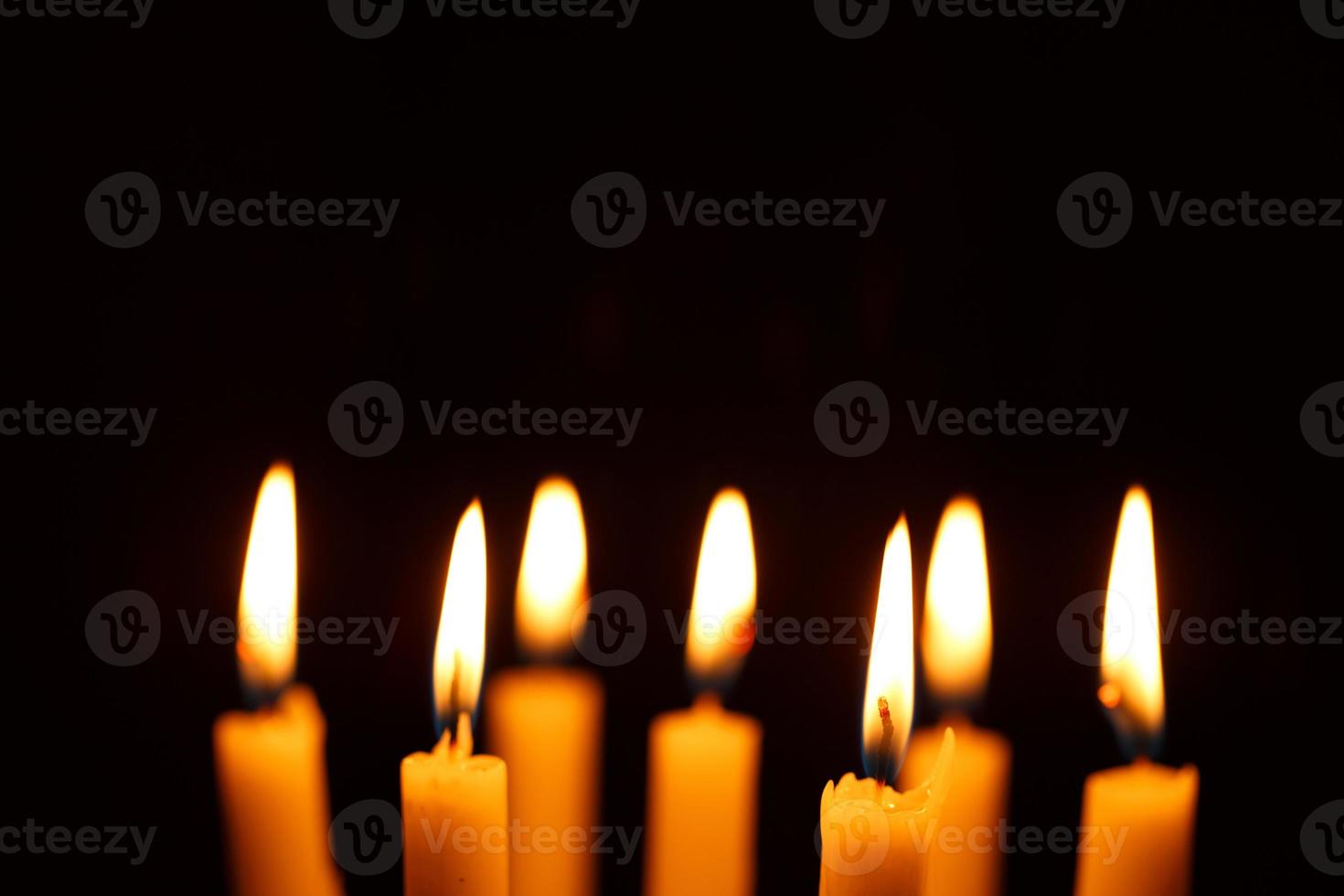 Many burning candles on black photo