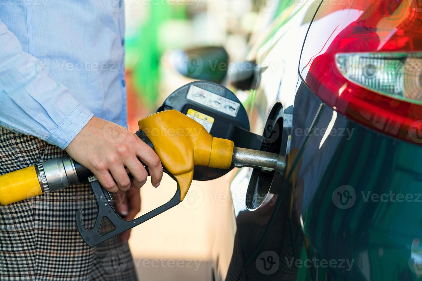 Woman fills petrol into the car at a gas station photo