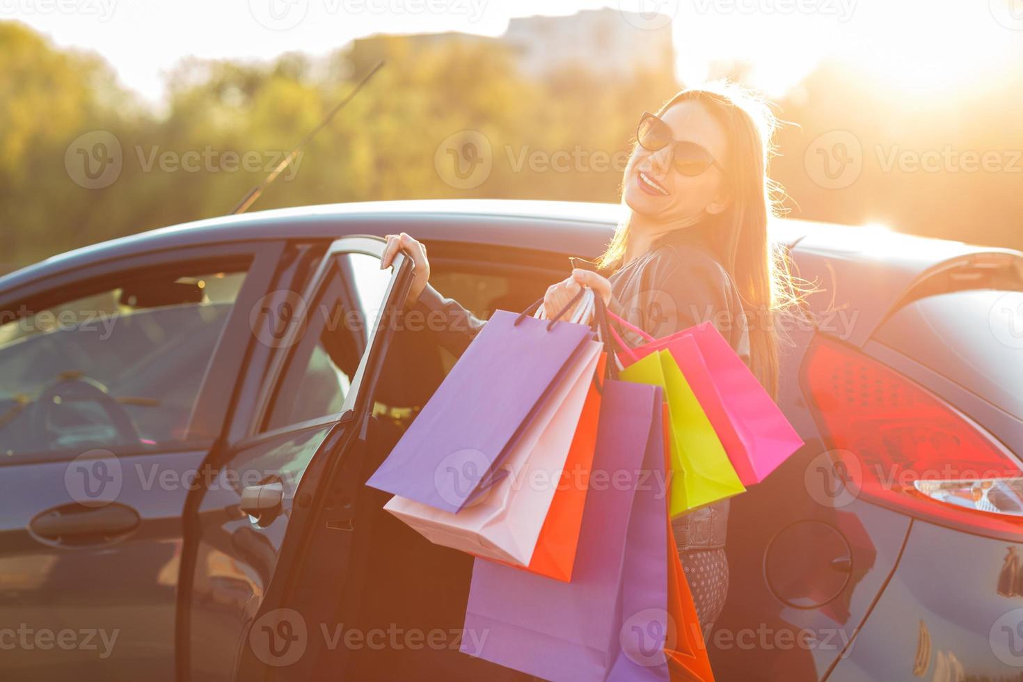 sonriente caucásico mujer poniendo su compras pantalones dentro el coche foto