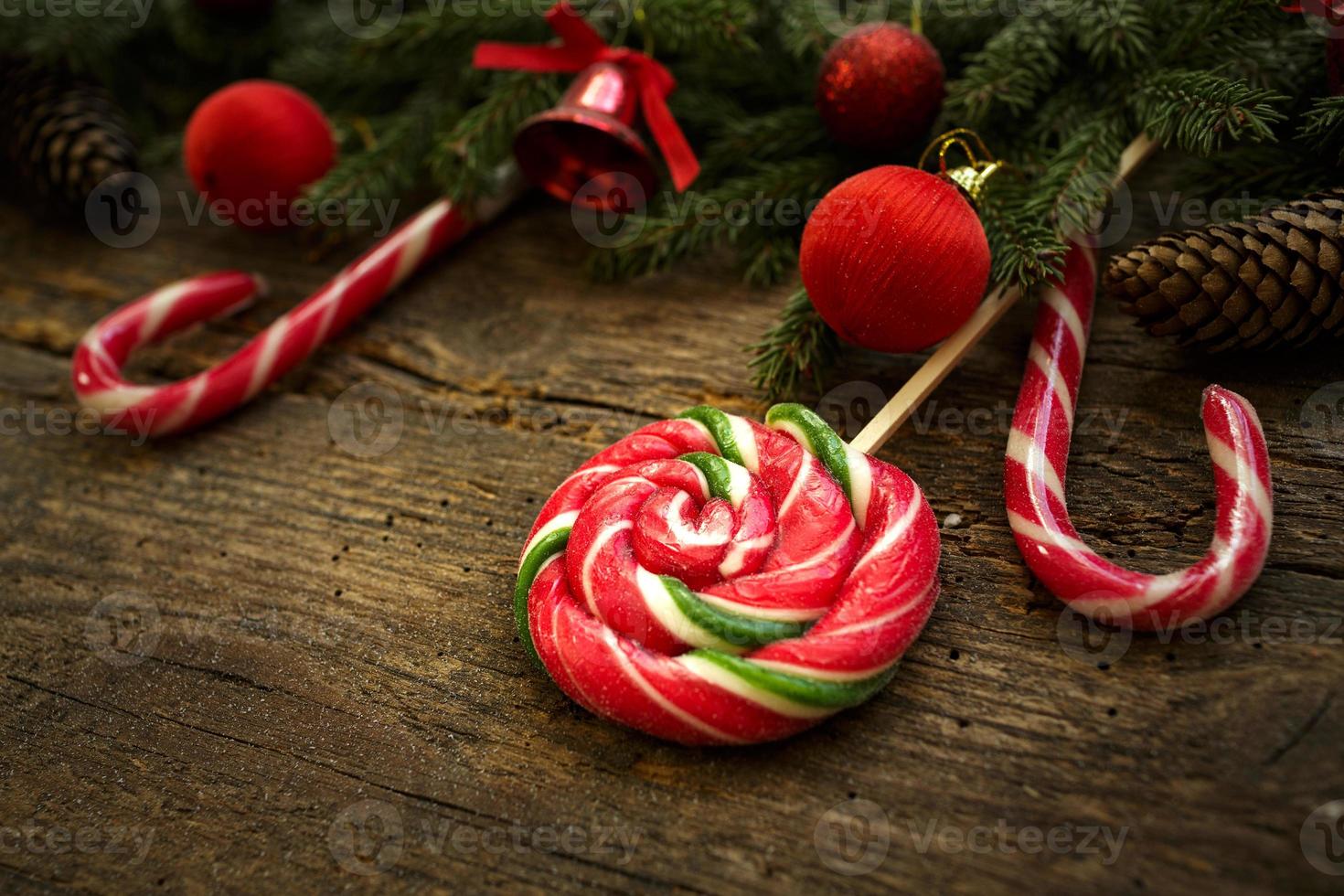 Christmas border with fir tree branches, cones, christmas decorations and candy cane on rustic wooden boards photo
