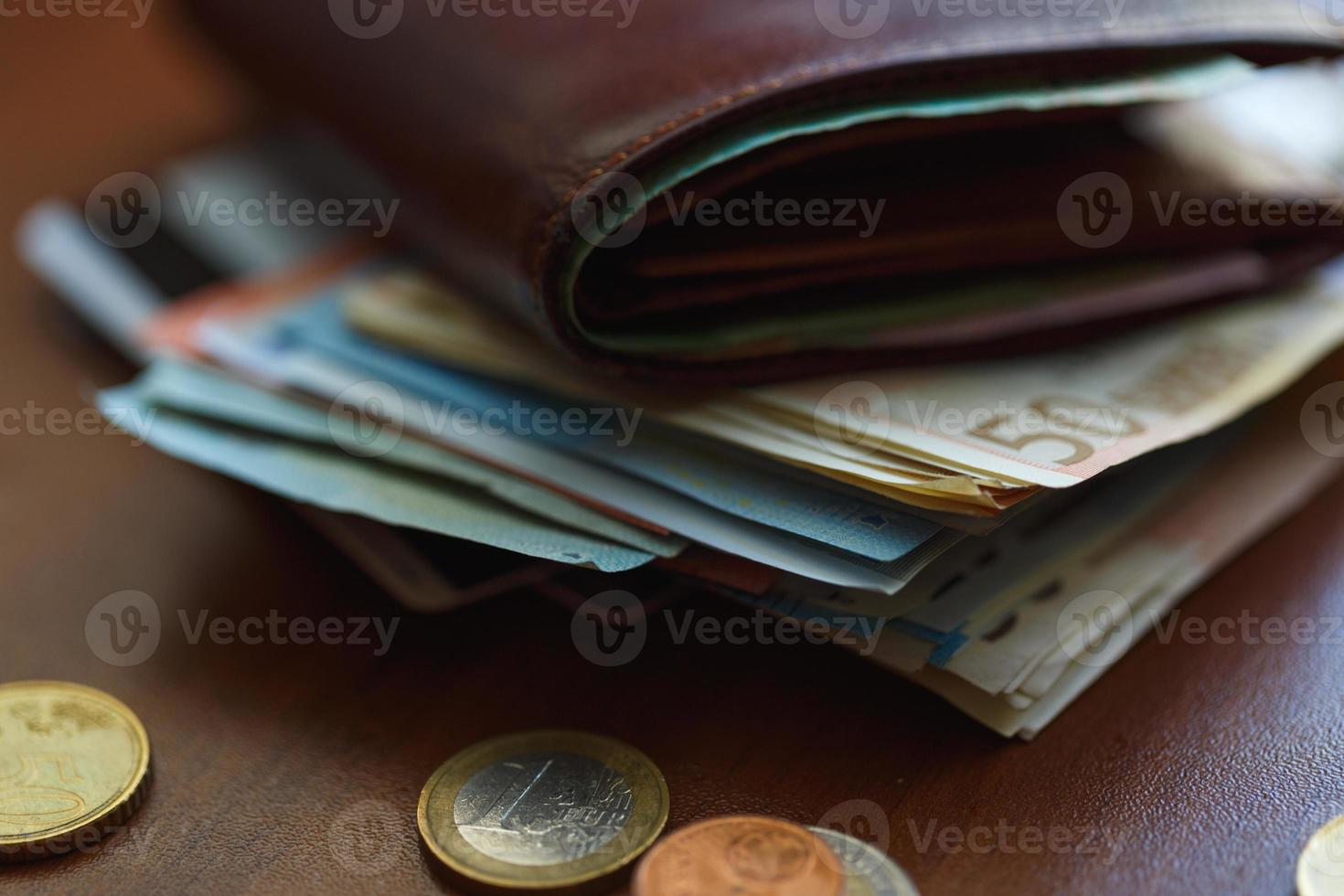 Brown wallet with euro money inside and coins, credit cards near it photo