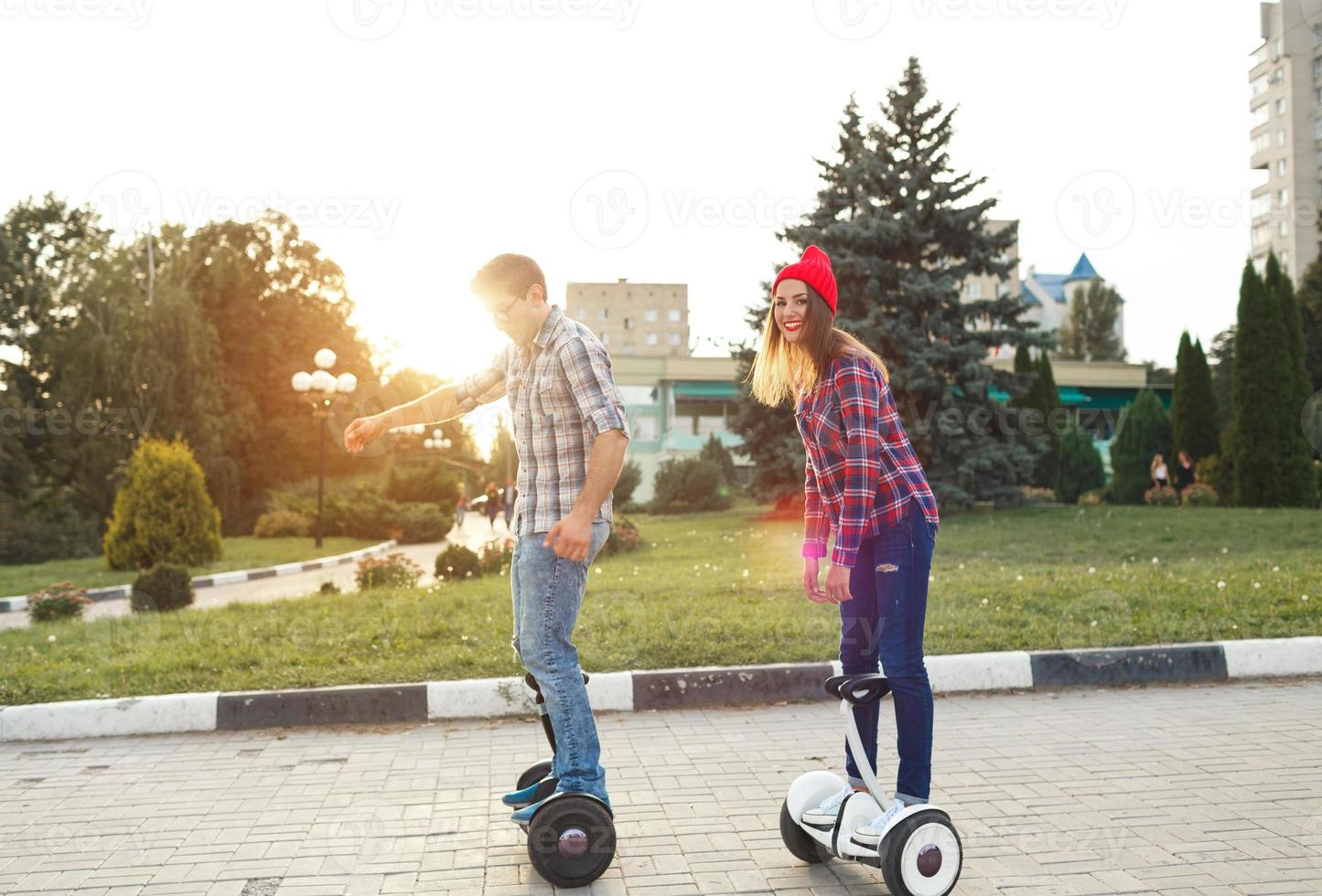 A young couple riding hoverboard - electrical scooter, personal eco transport, gyro scooter, smart balance wheel photo