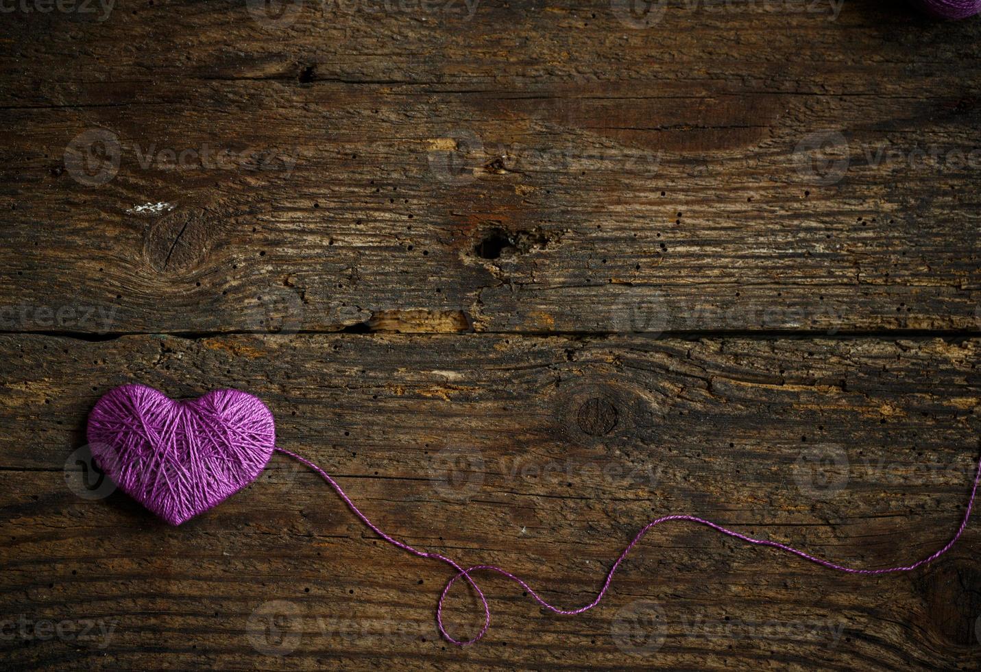Purple Heart with a ball of thread on on old shabby wooden background photo