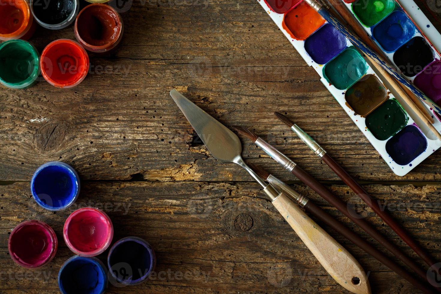 Watercolors and paint brush on wooden background photo