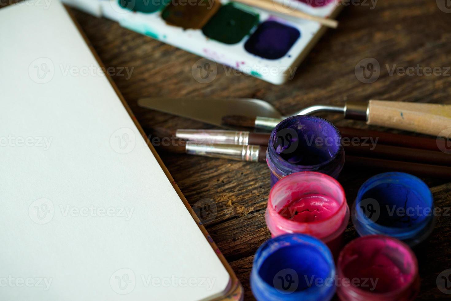 Paper, watercolors and paint brush on wooden background photo