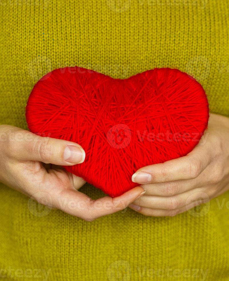 Closeup on red heart made from wool in hand of woman photo