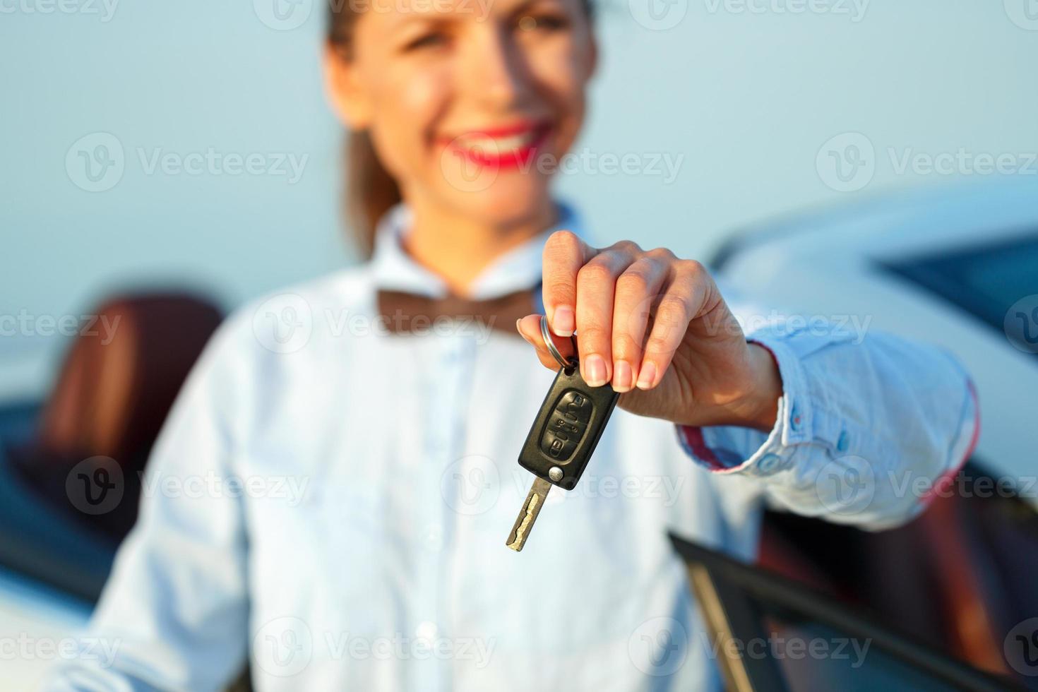 Young woman standing near a convertible with keys in hand photo