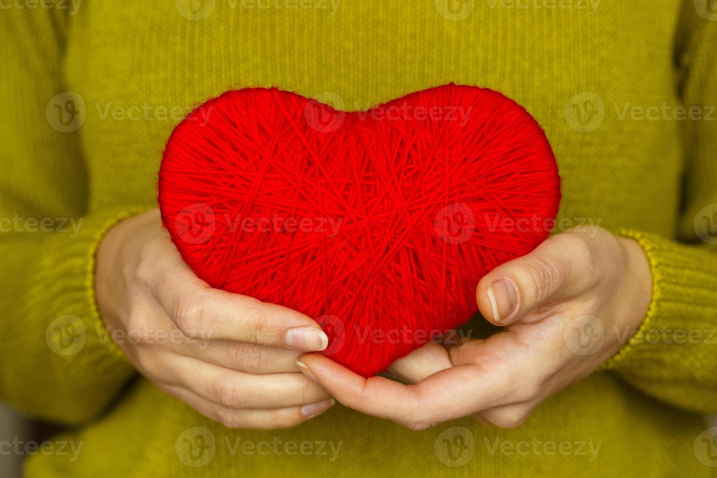 Closeup on red heart made from wool in hand of woman photo