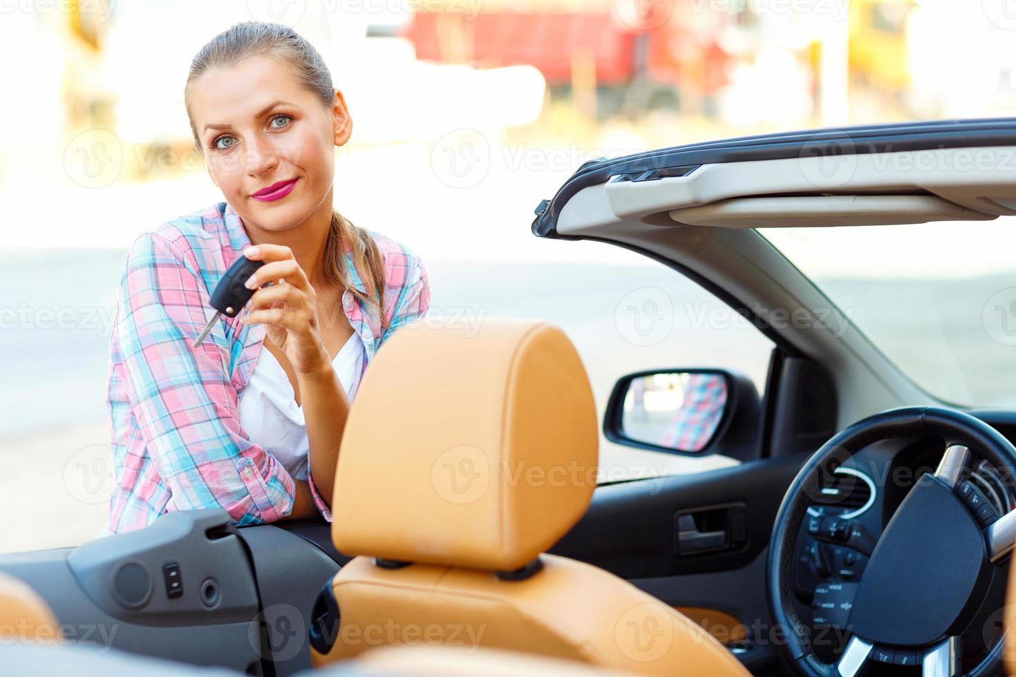 joven mujer en pie cerca un convertible con llaves en mano foto