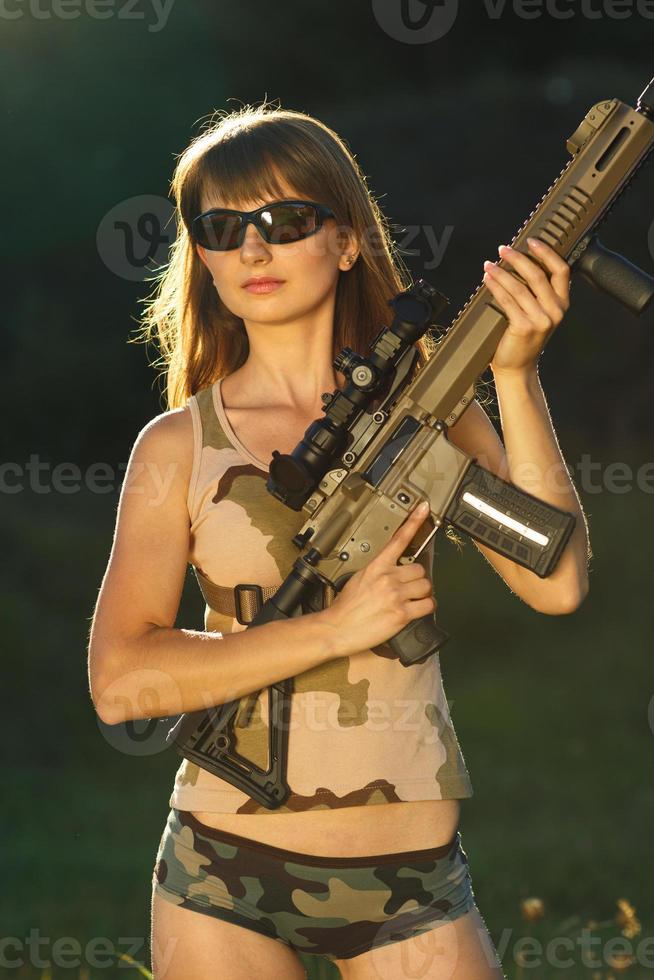 Young beautiful girl with a shotgun in an outdoor photo