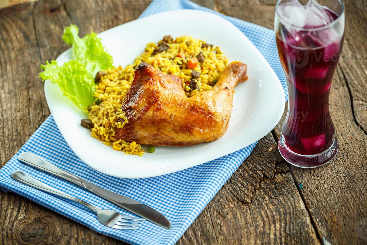 Tasty dishes from chicken thigh with rice and lettuce and a glass of juice with ice photo