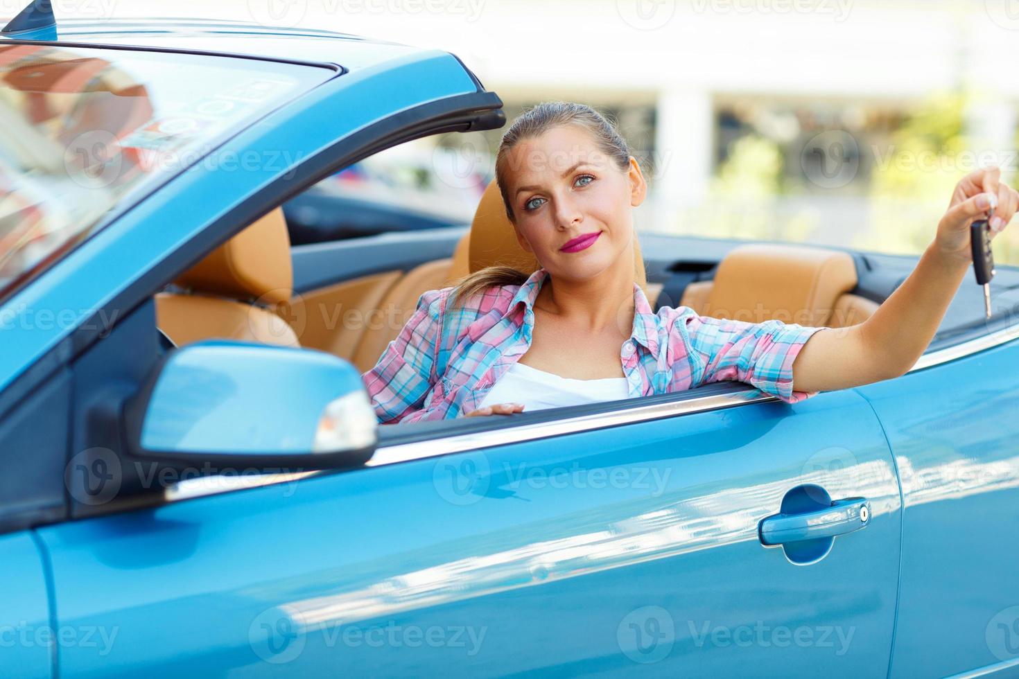 joven bonito mujer sentado en un convertible coche con el llaves en mano foto