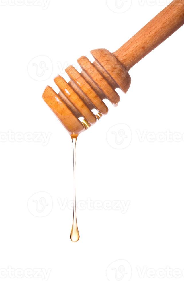 Honey dripping from a wooden dipper photo