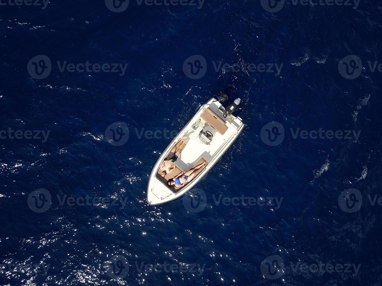 Aerial survey of a couple on a boat sunbathe together on a warm summer day photo