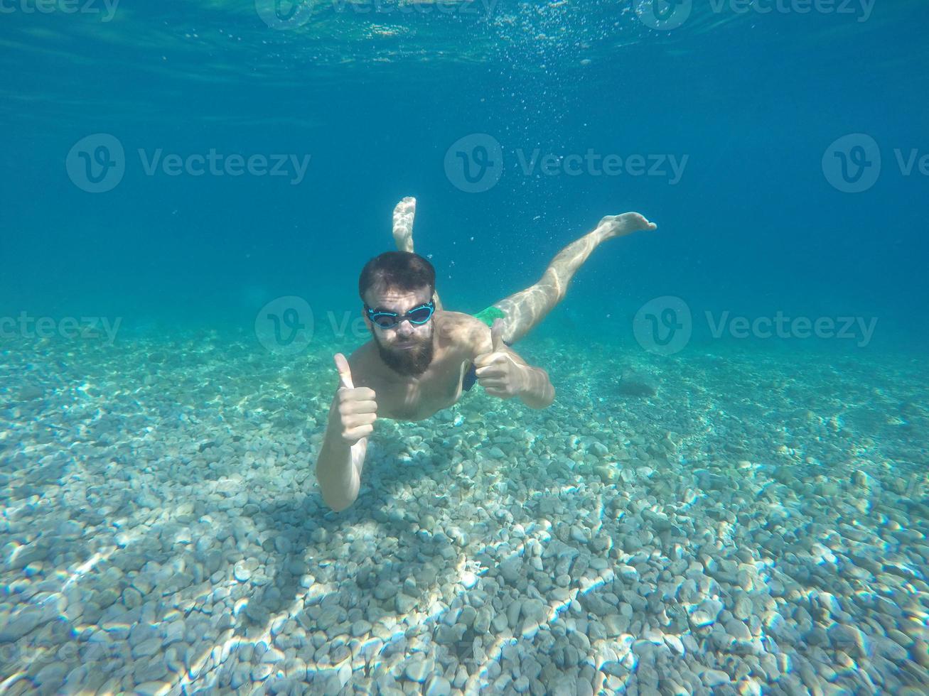 Young beard man with mask diving in a clean water photo