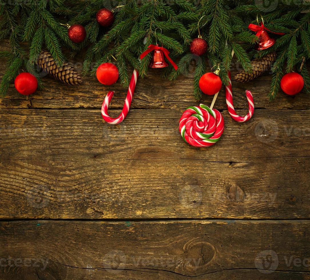 Christmas border with fir tree branches, cones, christmas decorations and candy cane on rustic wooden boards photo
