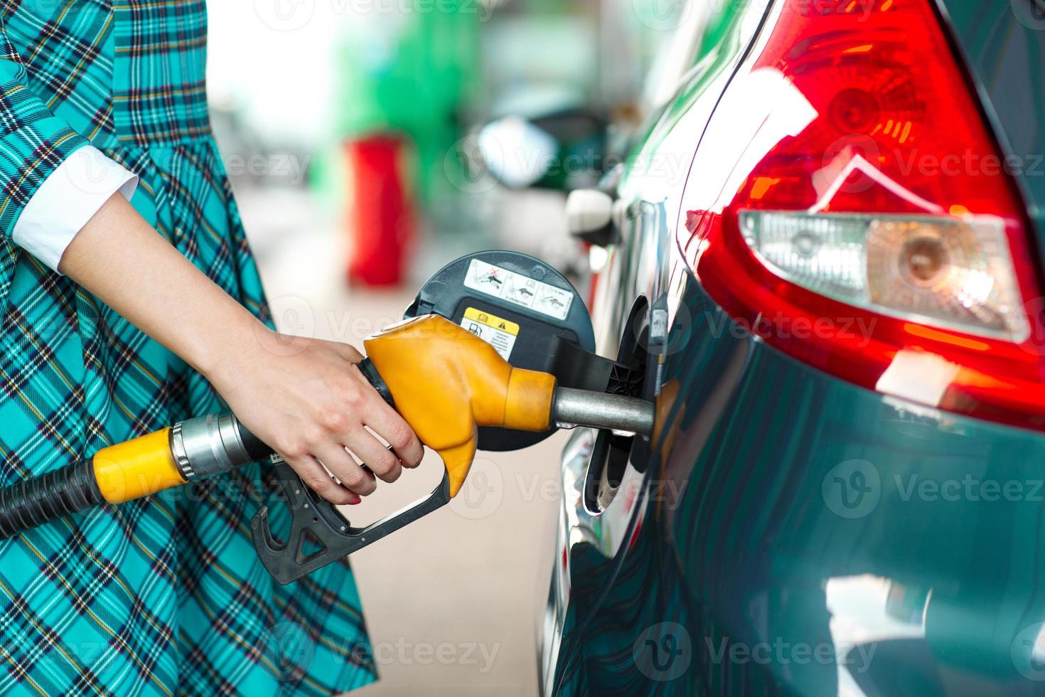 Woman fills petrol into her car at a gas station photo