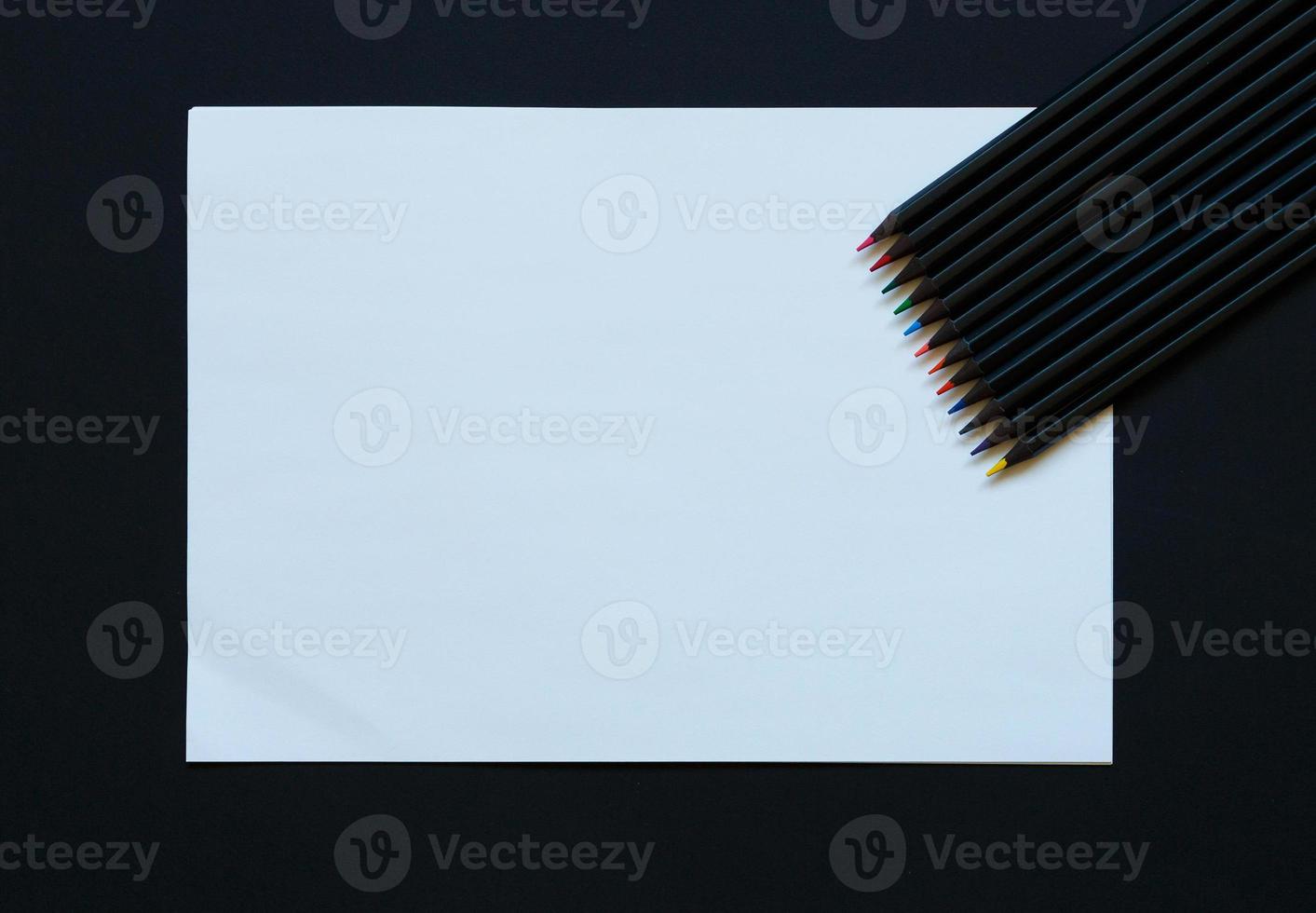 Blank paper and colorful pencils on black background photo