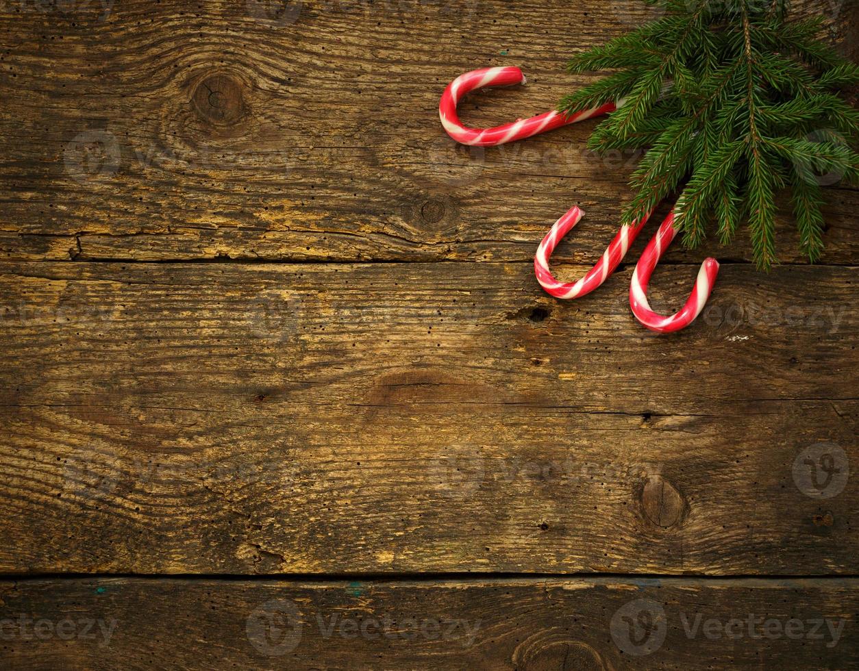 Christmas tree branches with candy canes on wooden texture ready for your design photo