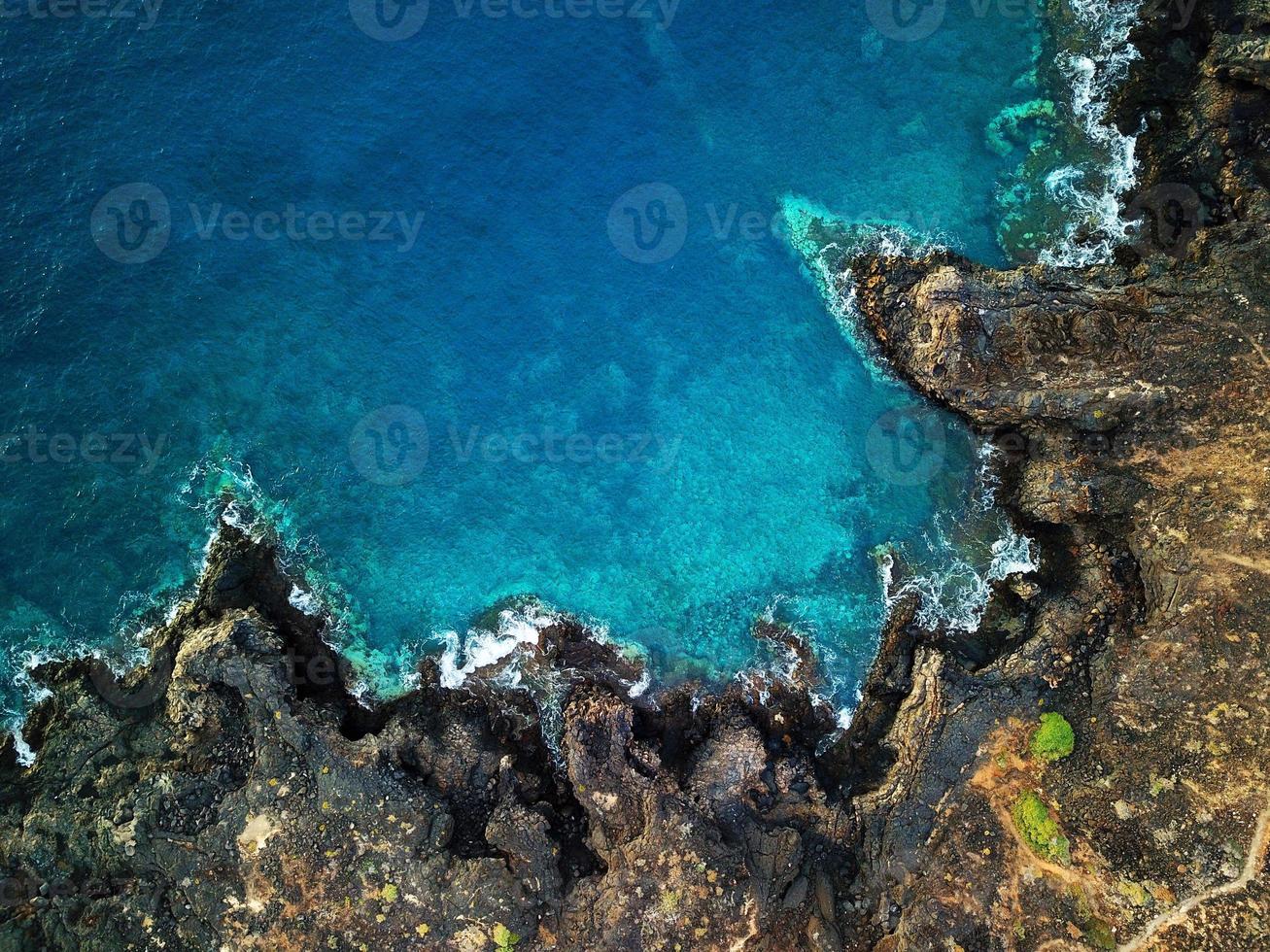 Top view of a deserted coast. Rocky shore of the island of Tenerife. Aerial drone footage of sea waves reaching shore photo