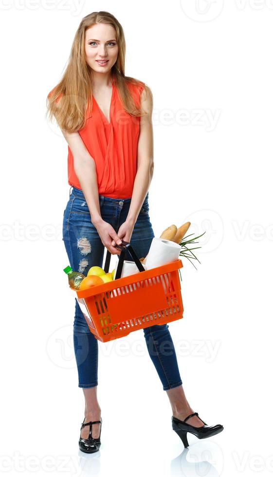 Happy young woman holding a basket full of healthy food on white. Shopping photo