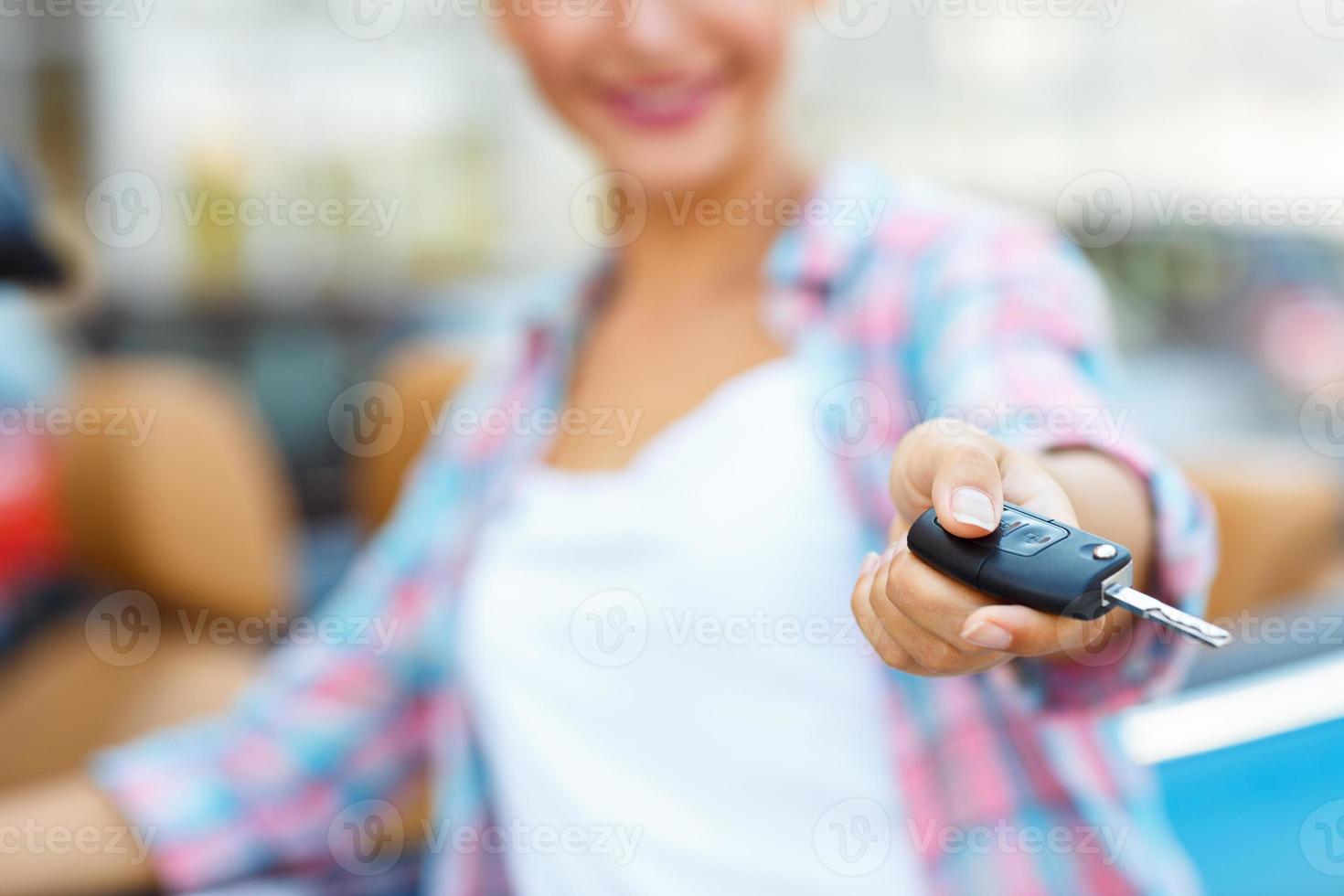 Young woman standing near a convertible with keys in hand photo