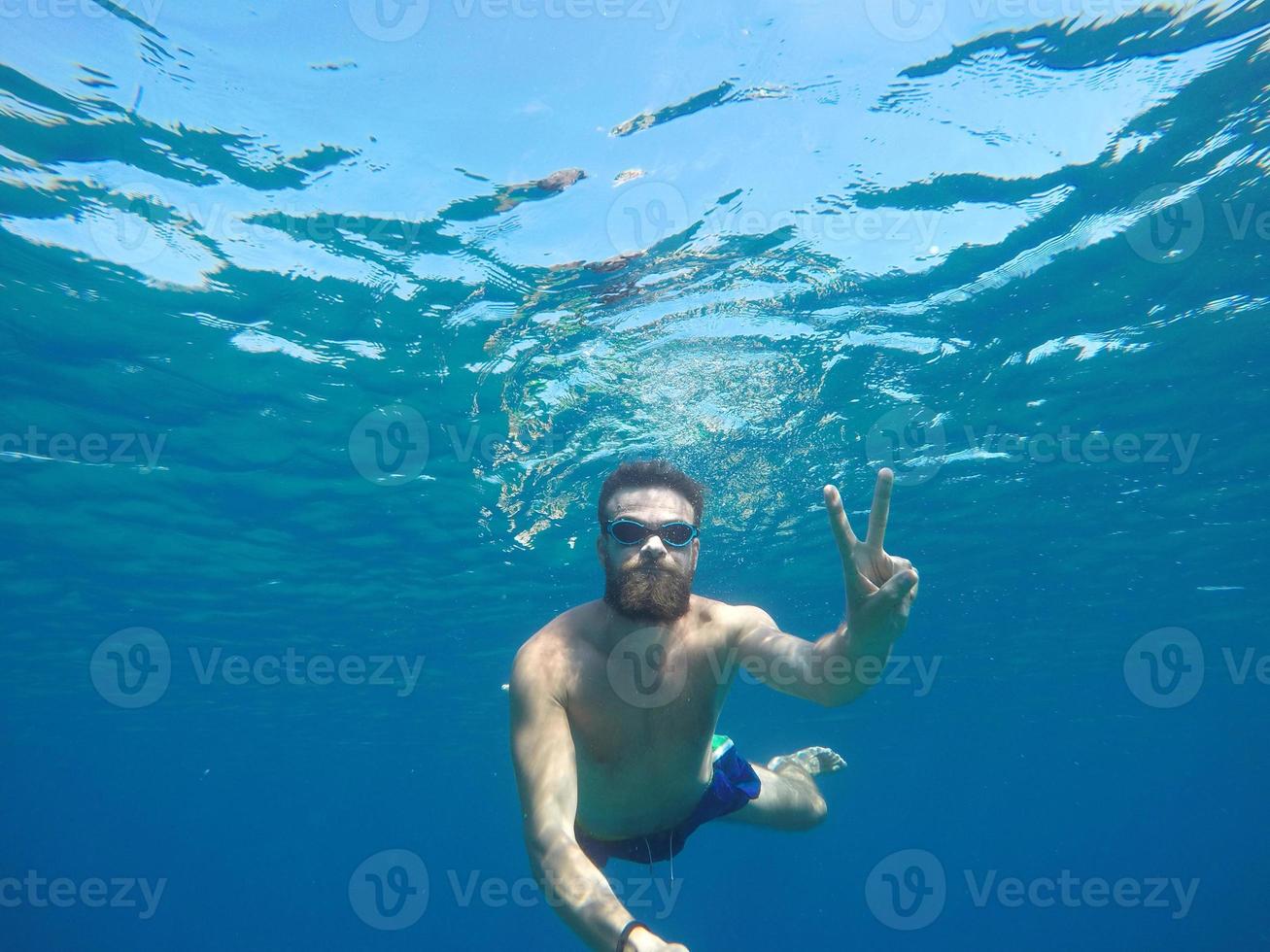 Young beard man with mask diving in a clean water photo