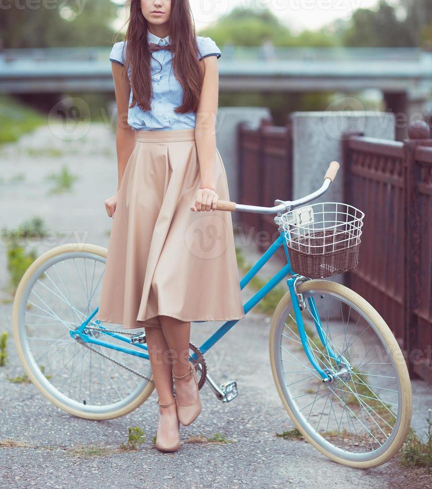 joven bella mujer, elegantemente vestida con bicicleta. belleza, moda y estilo de vida foto