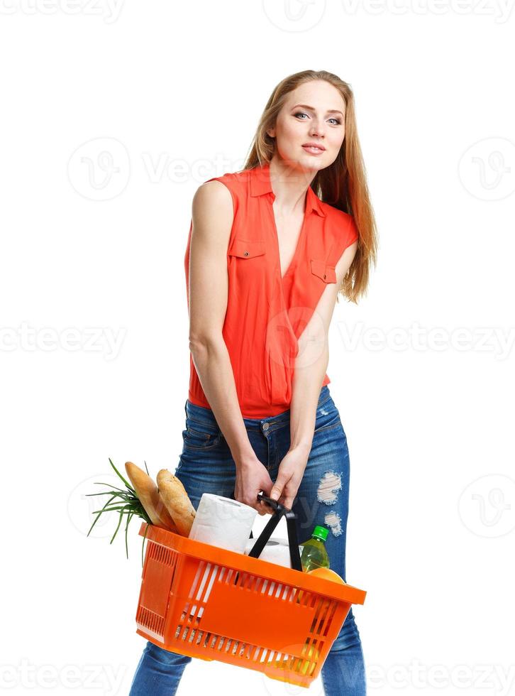 Happy young woman holding a basket full of healthy food on white. Shopping photo