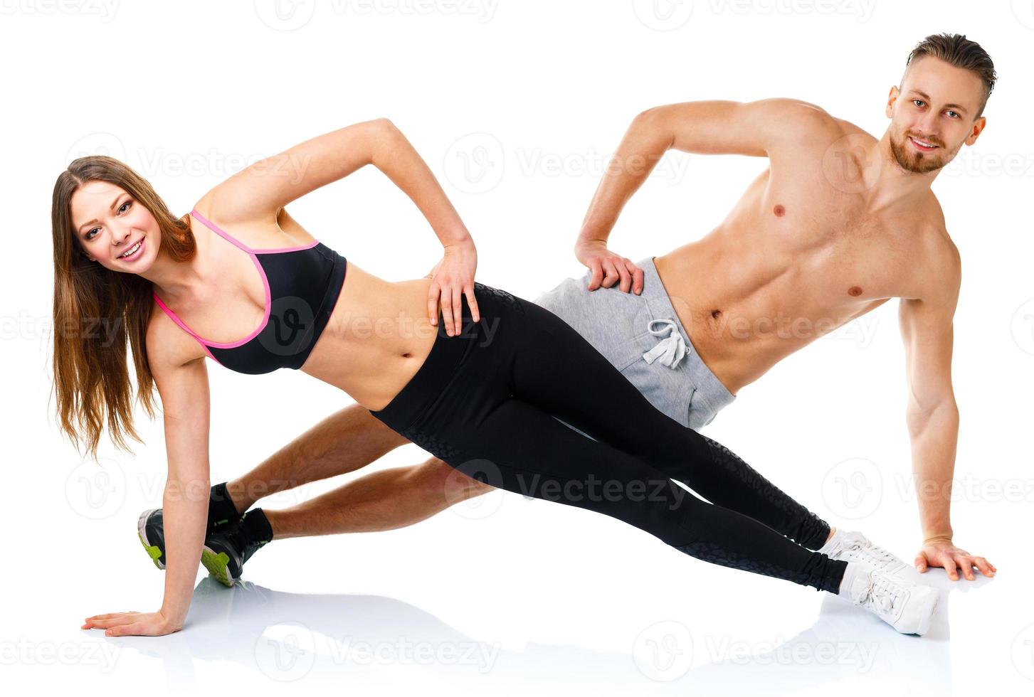 Attractive sport couple - man and woman doing fitness exercises on the white photo