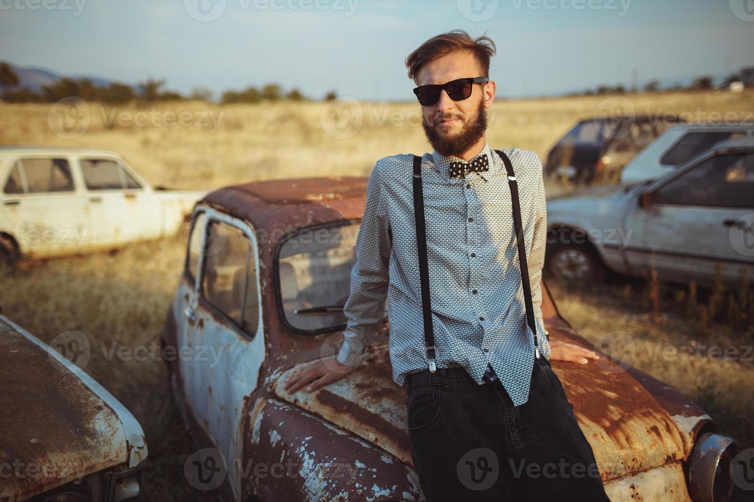 Young handsome stylish man, wearing shirt and bow-tie with old cars photo