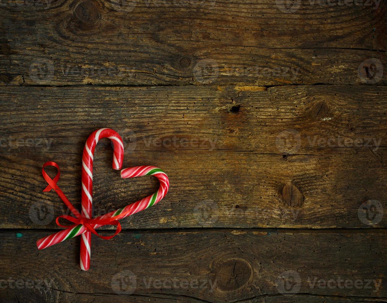 Candy canes in the heart shape on a wooden background photo
