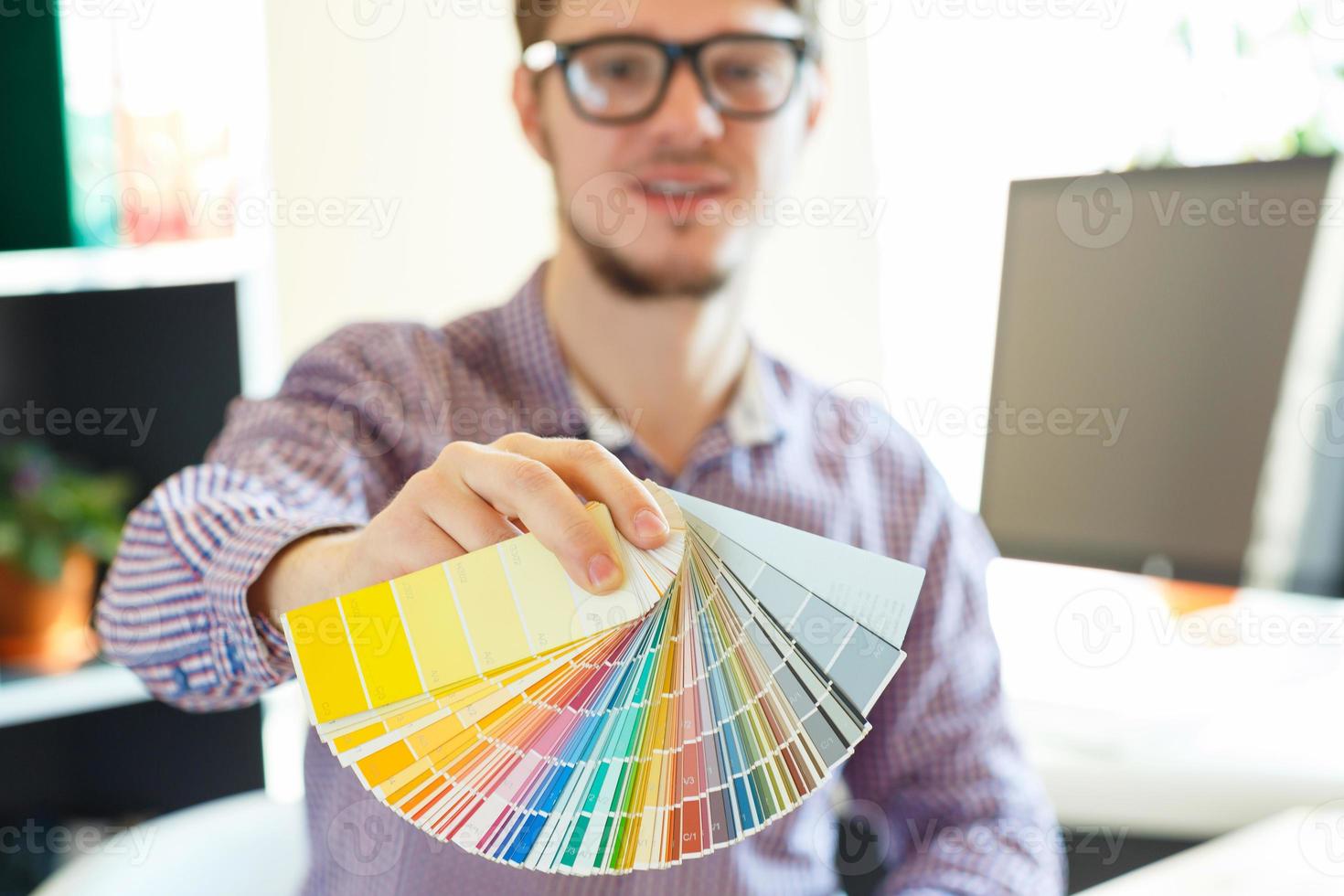 Young man looking to a color paint palette photo