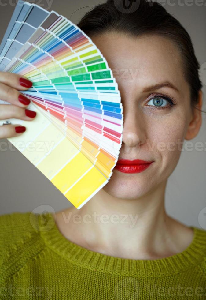 Woman with a red lips looking to a color paint palette photo