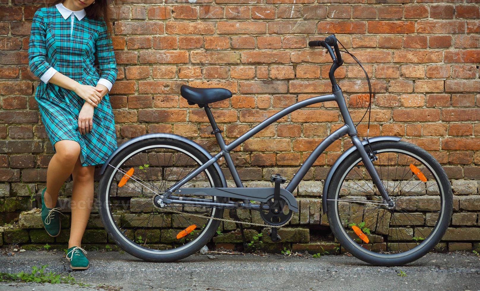 negro bicicleta y un niña cerca eso en el antiguo ladrillo pared antecedentes foto