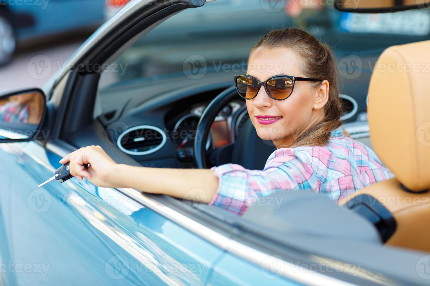 mujer en Gafas de sol sentado en un convertible coche con el llaves en mano - concepto de comprando un usado coche o un alquiler coche foto