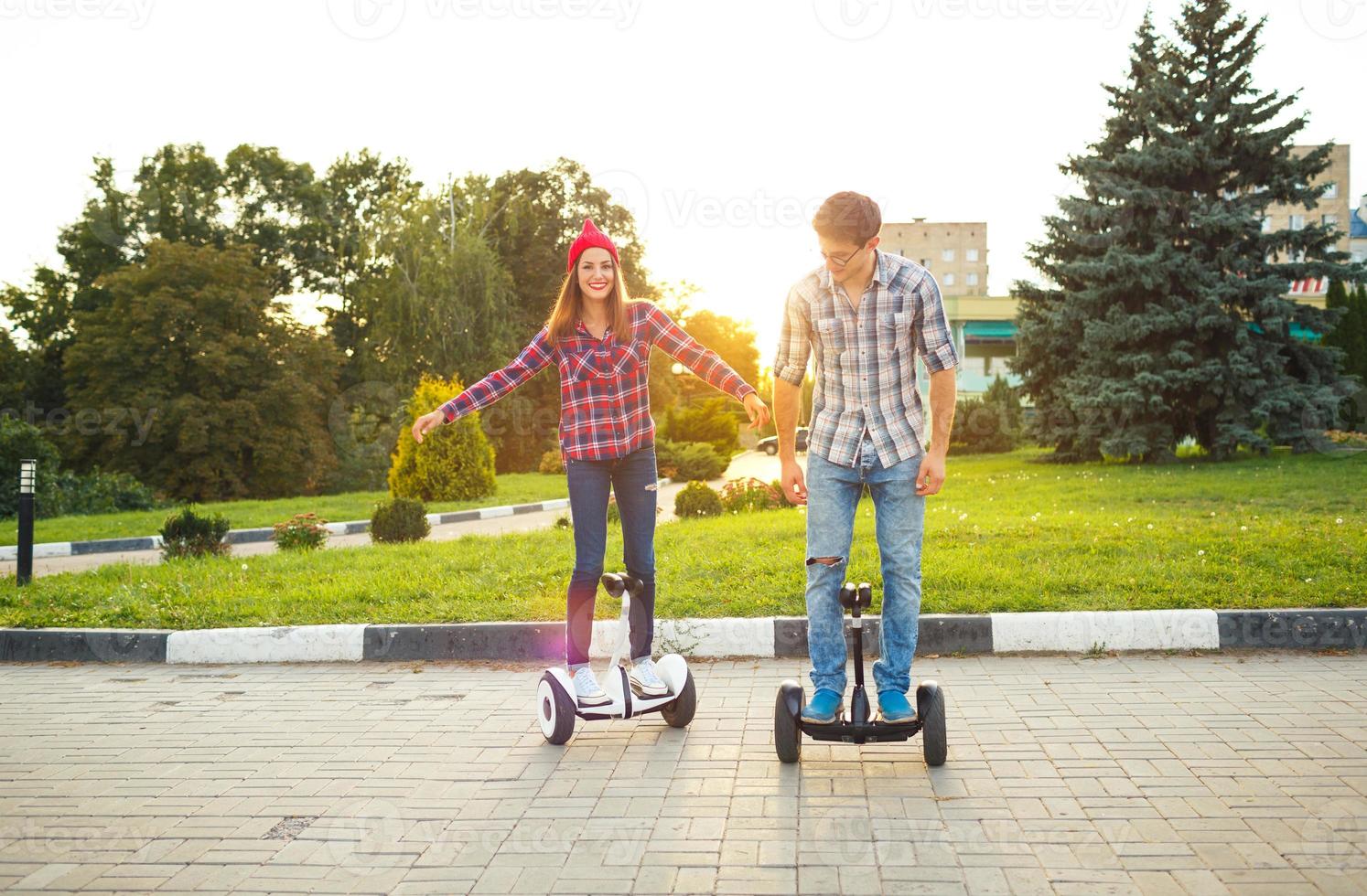 A young couple riding hoverboard - electrical scooter, personal eco transport, gyro scooter, smart balance wheel photo