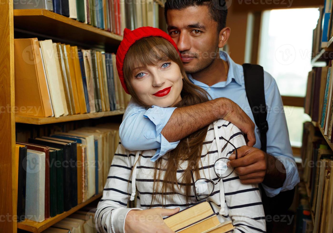 Young student couple choosing books in the library photo